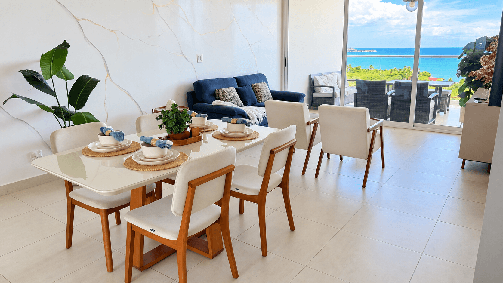 Comedor preparado con vajilla junto a los ventanales