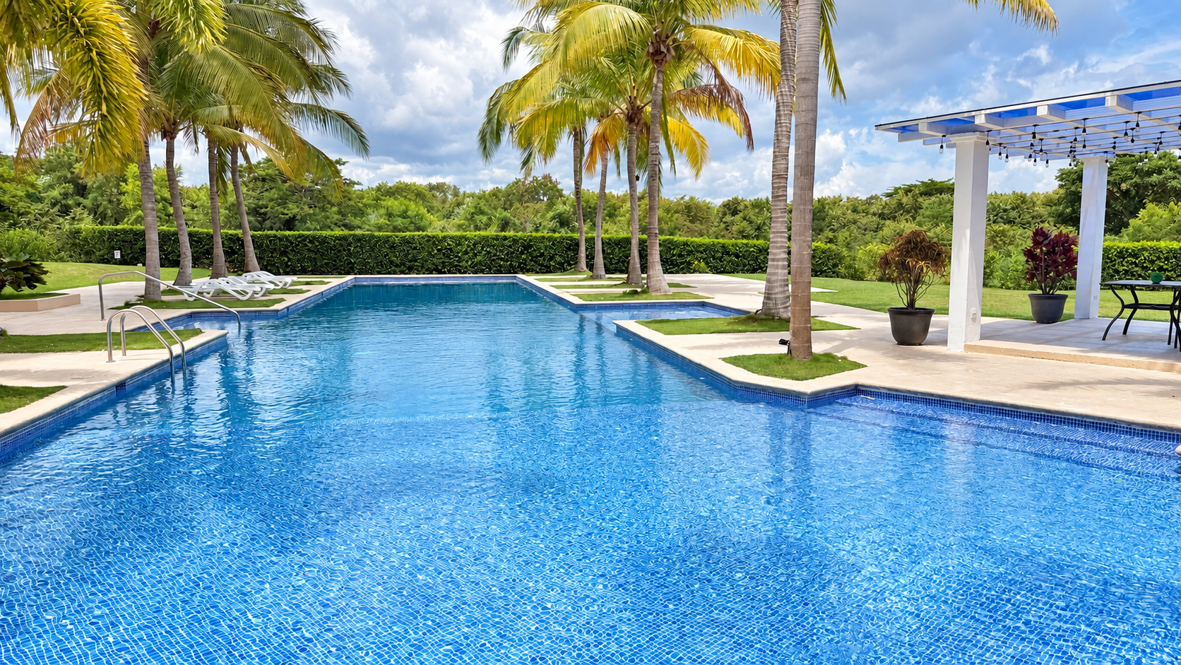 Piscina del complejo con pérgola y jardines